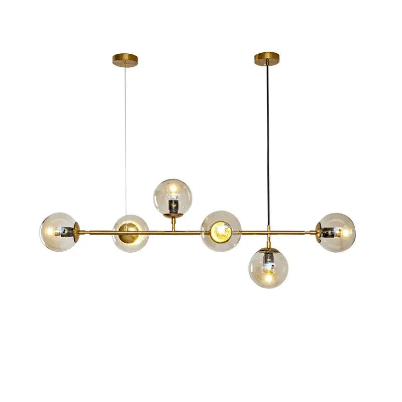Modern brass pendant lights with six spherical glass globes and exposed filament bulbs for dining room use