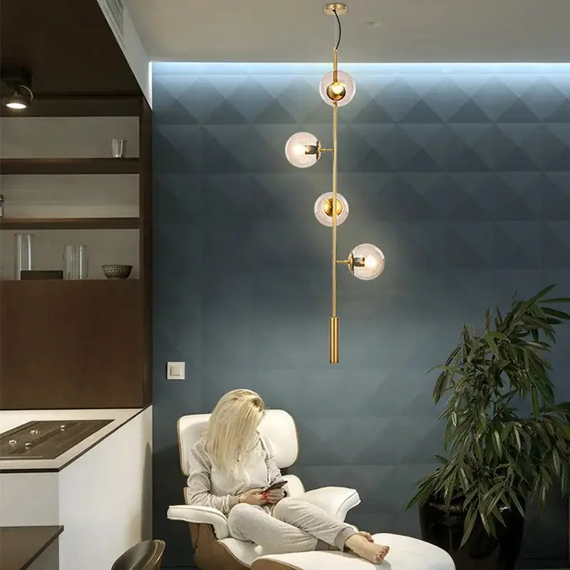 Modern brass pendant lights featuring five gold-toned glass globes for dining room illumination
