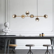Modern brass pendant lights featuring five spherical glass globes for dining room use with elegant design