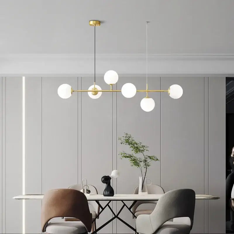 Modern brass pendant light with five golden glass ball frosted globes for elegant dining room lighting