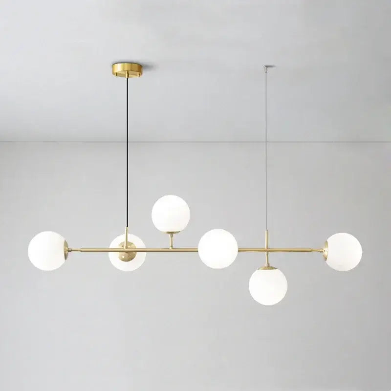 Modern brass pendant light with five frosted golden glass ball shades for dining room illumination