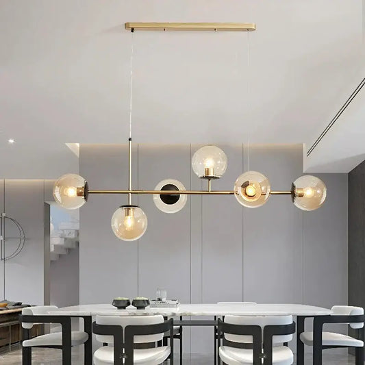 Modern brass pendant light with five spherical glass globes and central circular accent works beautifully for kitchen islands