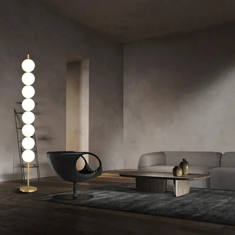 Modern brass floor lamp with six glowing white spherical bulbs on a slender gold-toned brass floor lamp stand for decorbites