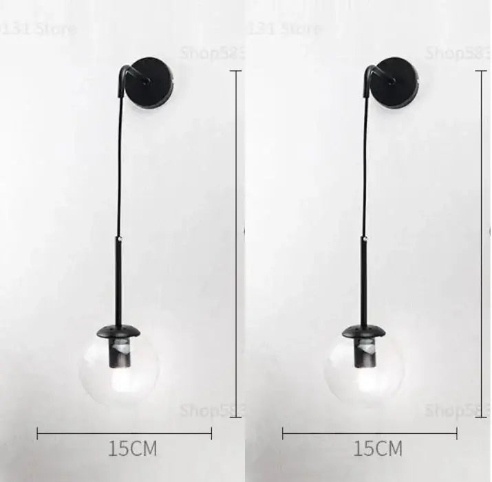 Black wall light with decorbites glass ball led clear globe and slender metal stem for modern bedroom sconce decor