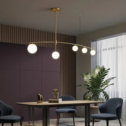 Modern brass glass ball pendant chandelier with five white glass bulbs in a gold-toned arc for dining room decorbites glass ball