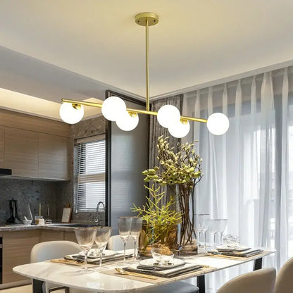 Modern brass glass ball pendant chandelier with gold-toned finish and five white spherical bulbs for dining room decorbites glass ball