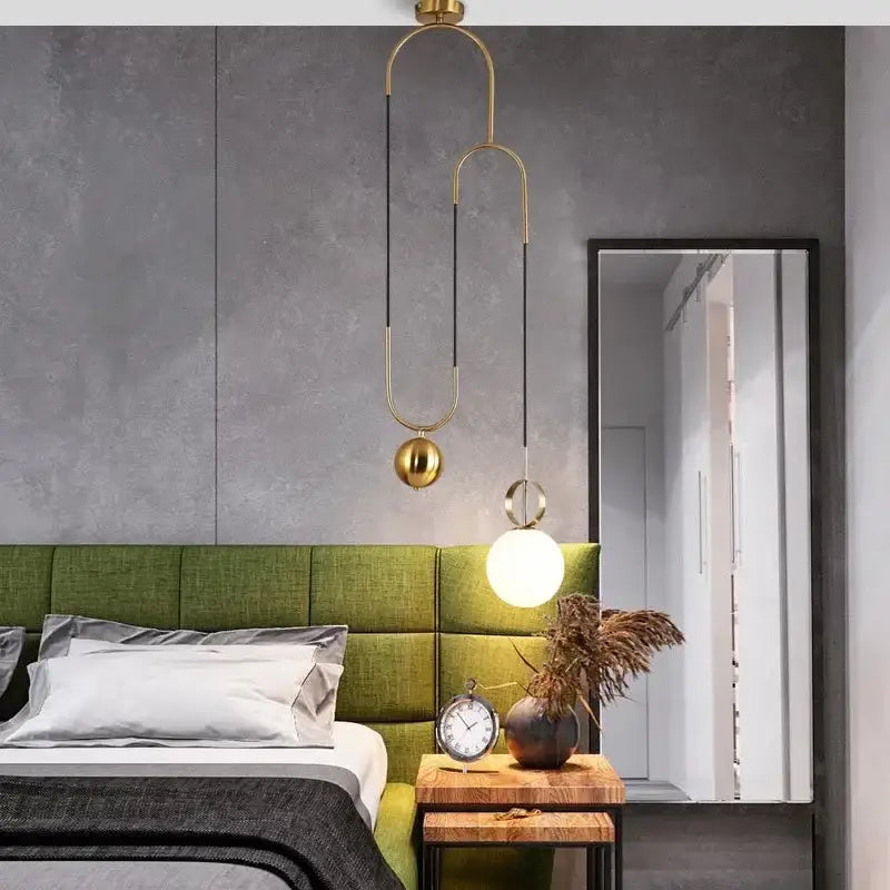 Modern brass glass ball pulley pendant light with gold-toned curved metal arms and spherical glass shades over bed