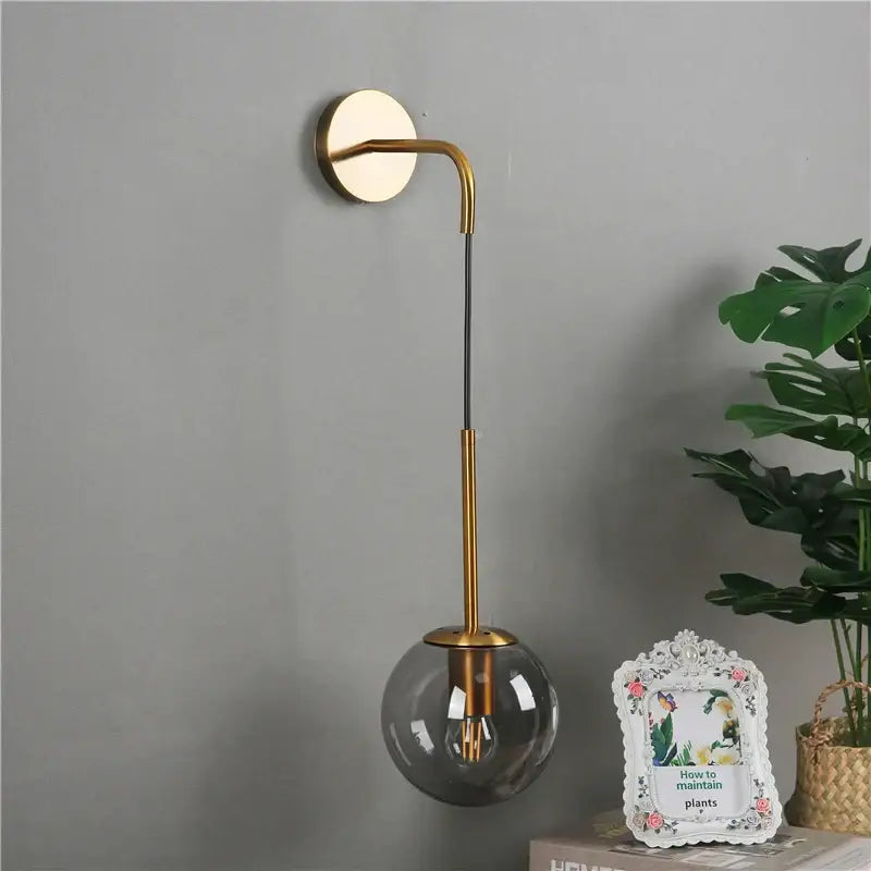 Modern brass glass ball wall lamp with gold-toned curved arm and smoked glass shade for bedroom decorbites glass ball lighting