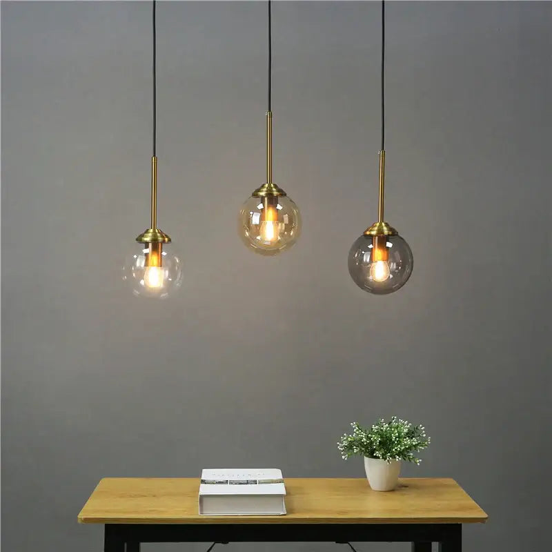 Modern brass glass ball wall lamps with clear amber and smoky glass shades hanging above a wooden table decorbites glass ball