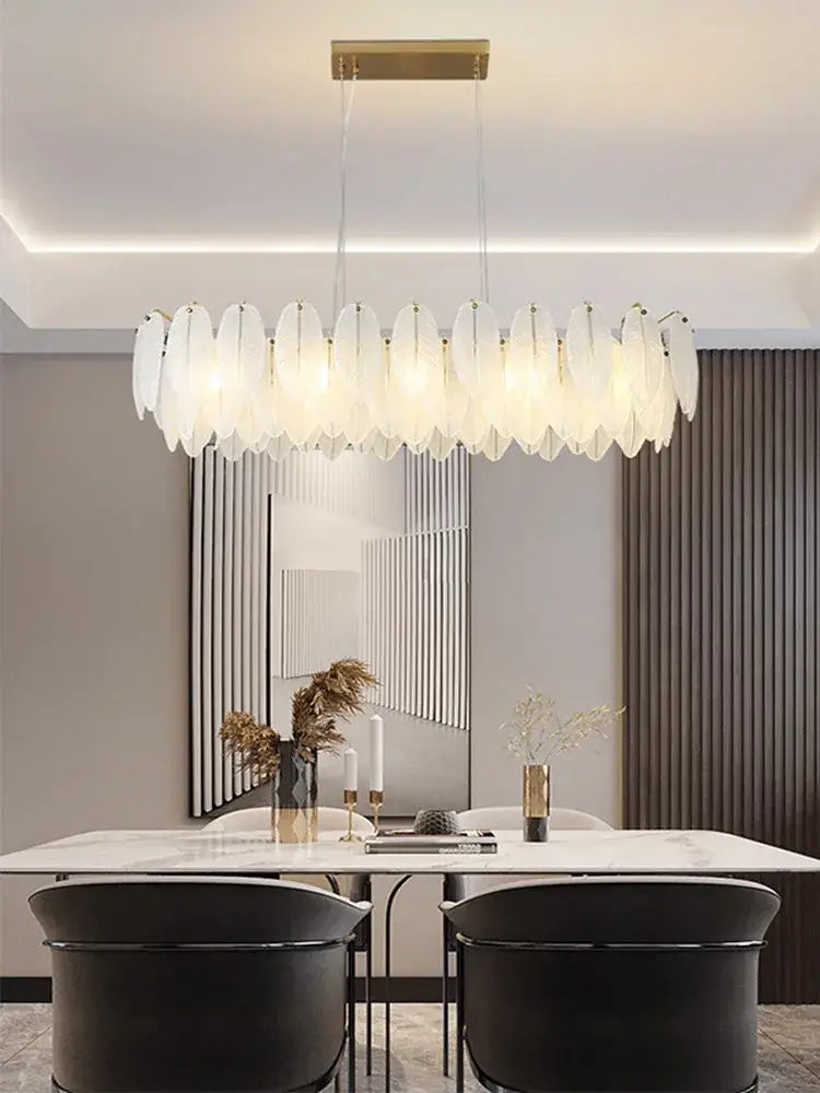 Modern brass glass feather chandelier with translucent white feather shades suspended from gold ceiling mount for dining room