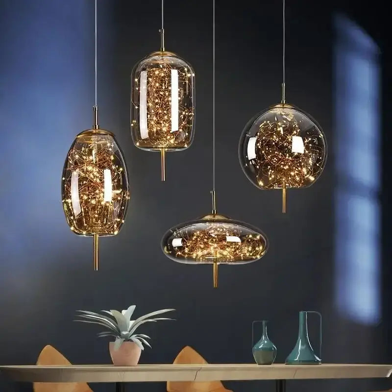 Four modern brass glass pendant lights with golden accents and warm glowing string lights for bedroom chandelier use