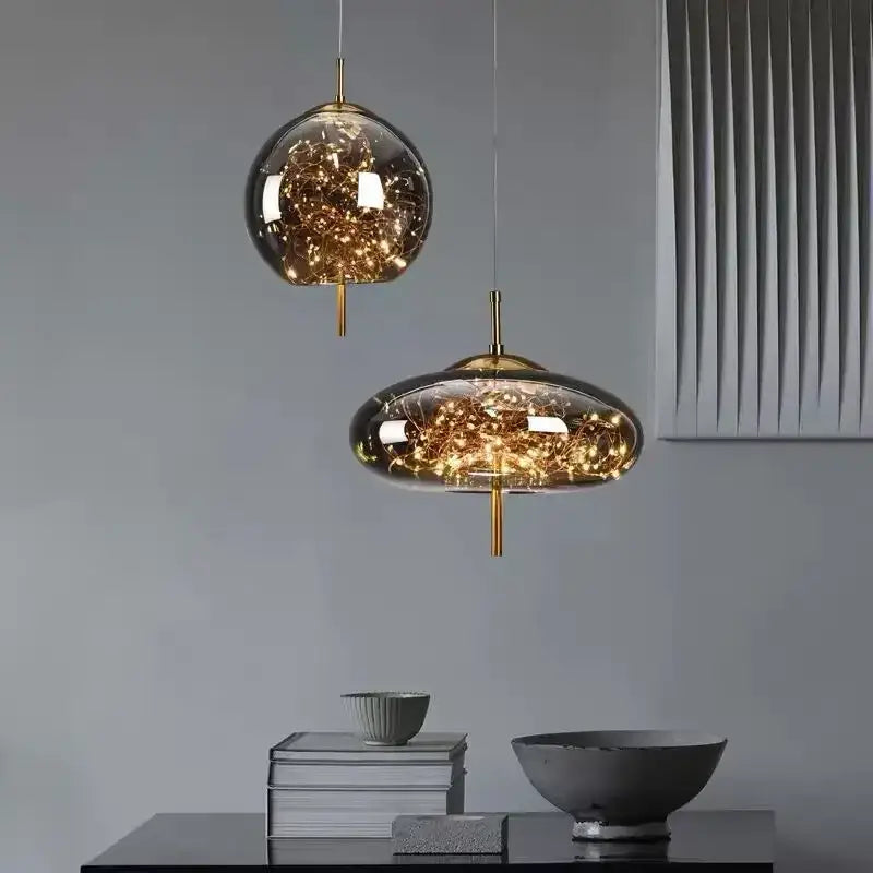 Modern brass glass pendant light with amber glass and warm fairy lights featuring spherical and oval shapes