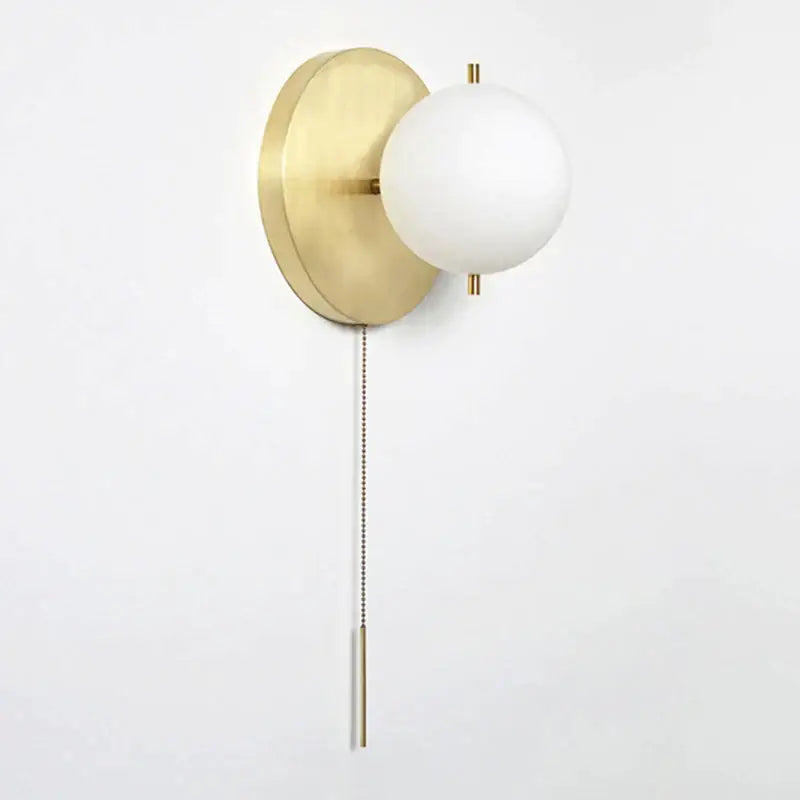 Modern brass glass round wall lamp with gold-toned wall sconce and frosted white spherical glass shade and pull chain
