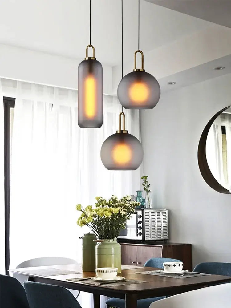 Three modern pendant lights with frosted glass shades and brass accents for a modern brass glass staircase chandelier