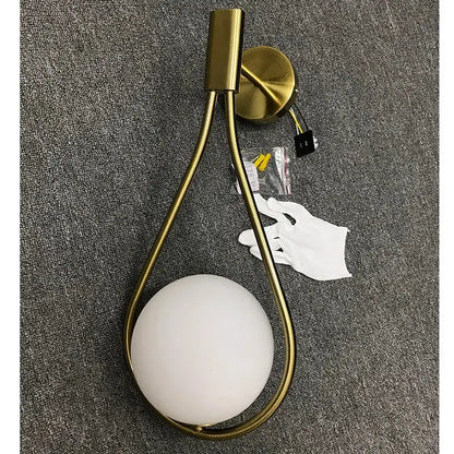 Modern brass glass wall lamp with a gold-toned teardrop frame and frosted white glass shade for bedroom lighting decorbites brass glass