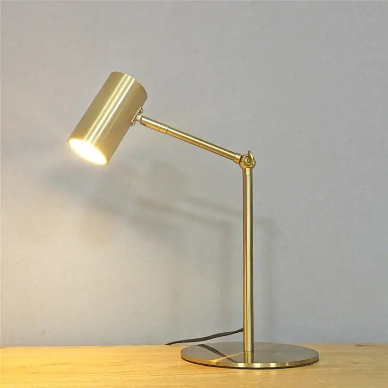 Modern brass golden table lamp with gold finish adjustable cylindrical head and slender articulated arm for reading desk light