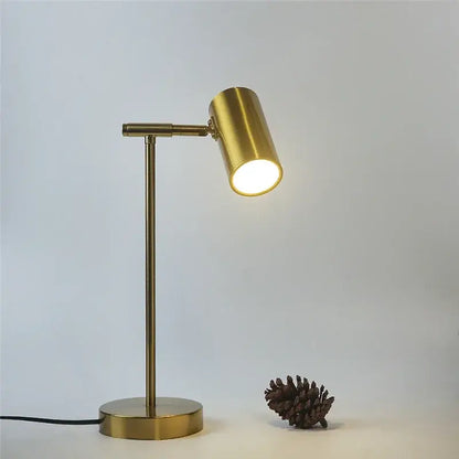 A sleek brass-finished adjustable golden table lamp with cylindrical head emitting warm light for study and reading