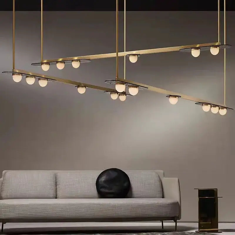 Modern brass pendant light fixture with multiple spherical gray glass led bulbs in intersecting horizontal bars