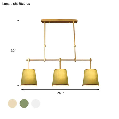 Modern brass pendant light with gold finish and three cylindrical white green flaxen fabric shades for dining room lighting