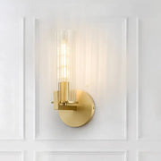 Modern brass wall sconce with a gold-toned finish and clear ribbed glass shade featuring an exposed filament bulb