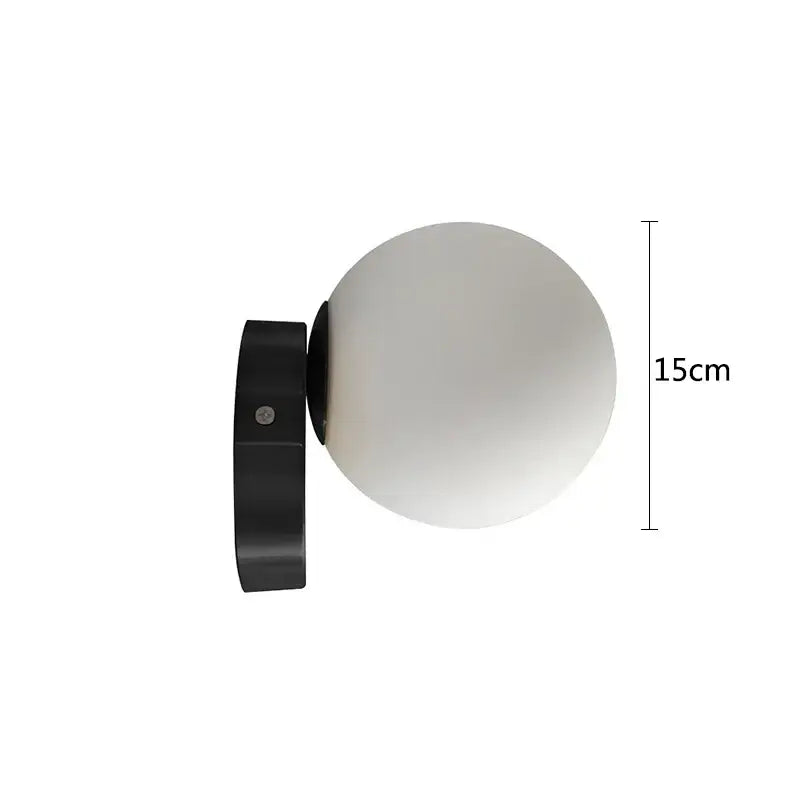 Modern brass round ceiling lamp with a sleek black wall-mounted base and frosted glass round spherical globe