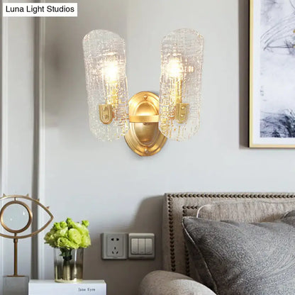 Modern brass sconce with two lights featuring gold-toned metal and clear water glass shades for living room use