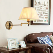Modern brass swing arm paper wall mount lamp with cream pleated fabric shade for living room use
