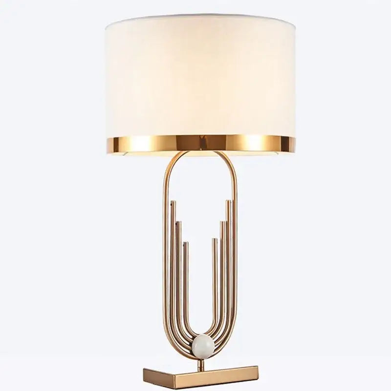 Modern decorbites brass table lamp with gold-toned metal base and off-white cylindrical fabric shade for bedroom decor