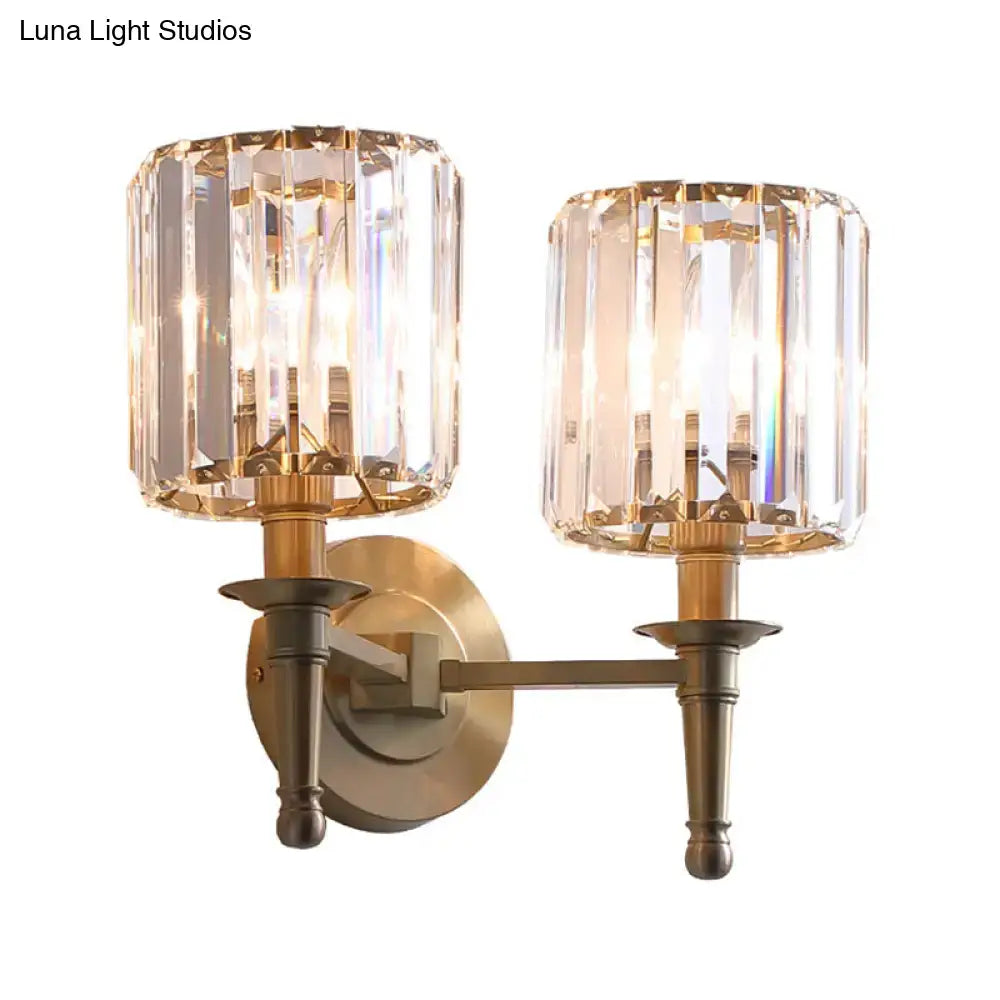 Modern brass wall light sconce with two faceted crystal shades designed as a bedroom wall lamp