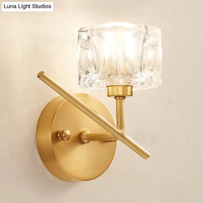 Modern brass wall light with gold-toned finish and a clear crystal shade for elegant bedroom sconce lighting