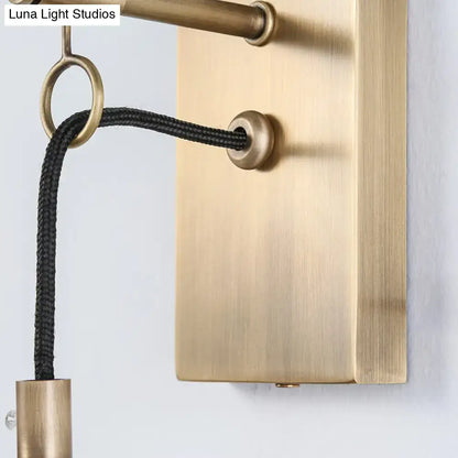 Modern brass wall mount lamp with brass finish rectangular backplate and black braided cord for bedroom lighting