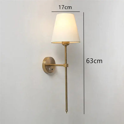A sleek brass wall sconce with a tapered white fabric shade featuring decorbites gold touch led for dining room decor