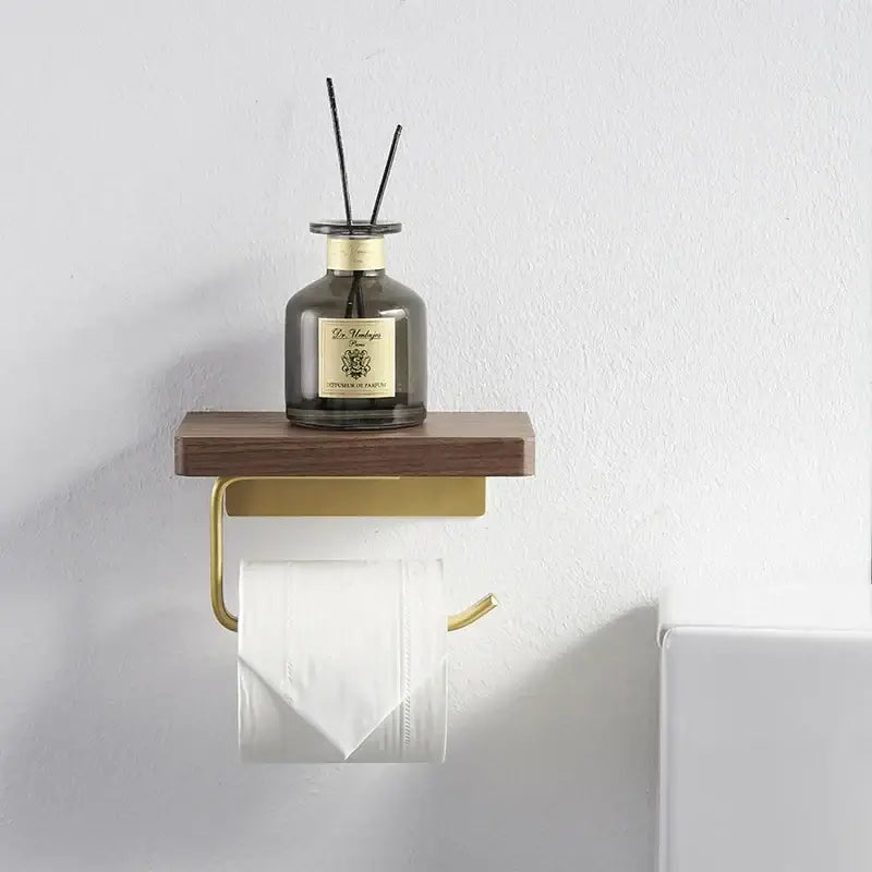 Modern brass and wood toilet paper holder with gold-toned wall-mounted paper holder and wooden shelf with diffuser bottle