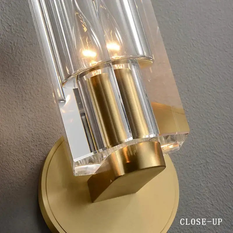 A modern wall lamp with clear faceted glass tubes and a brushed bronze copper crystal base for bedroom lighting decorbites