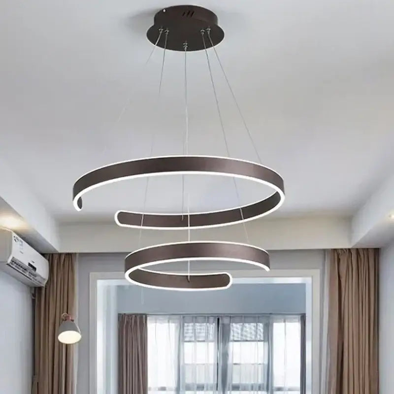 Modern bronze geometric pendant light fixture with three concentric spiraling rings and illuminated edges for dining room