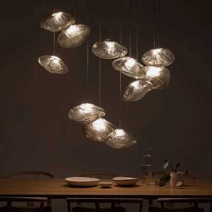 A modern bronze glass cloud chandelier pendant lamp with translucent frosted glass shades above a wooden table