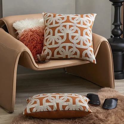 Orange and white geometric-patterned cushion cover with woven texture on tan leather chair for decorbites brown coffee decor