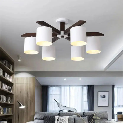 Modern brown and white ceiling mount chandelier with six white cylindrical shades and dark wood arms for living room