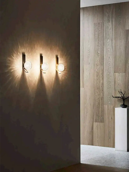Three modern wall sconce lamps with sleek black metal fixtures and frosted glass globes emitting warm light