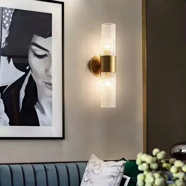 Modern brushed brass crystal wall lamp with gold-toned textured glass cylinder diffusing warm light for bedroom decorbites wall lamp