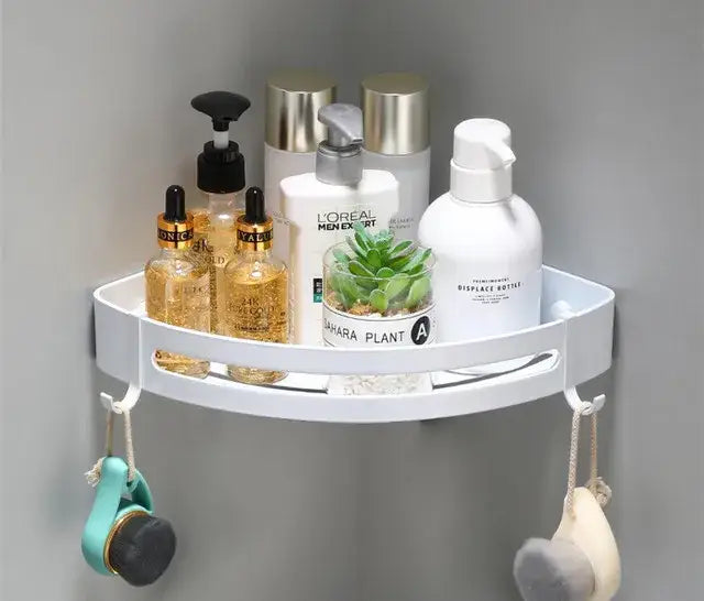 Modern brushed gold aluminum corner shelf holding toiletries and a small plant in a white bathroom corner shelf decorbites brushed gold