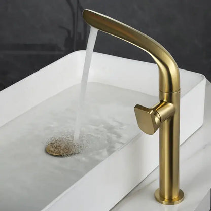 A sleek modern brushed gold basin faucet with a tall curved spout and square handle by decorbites on a white sink