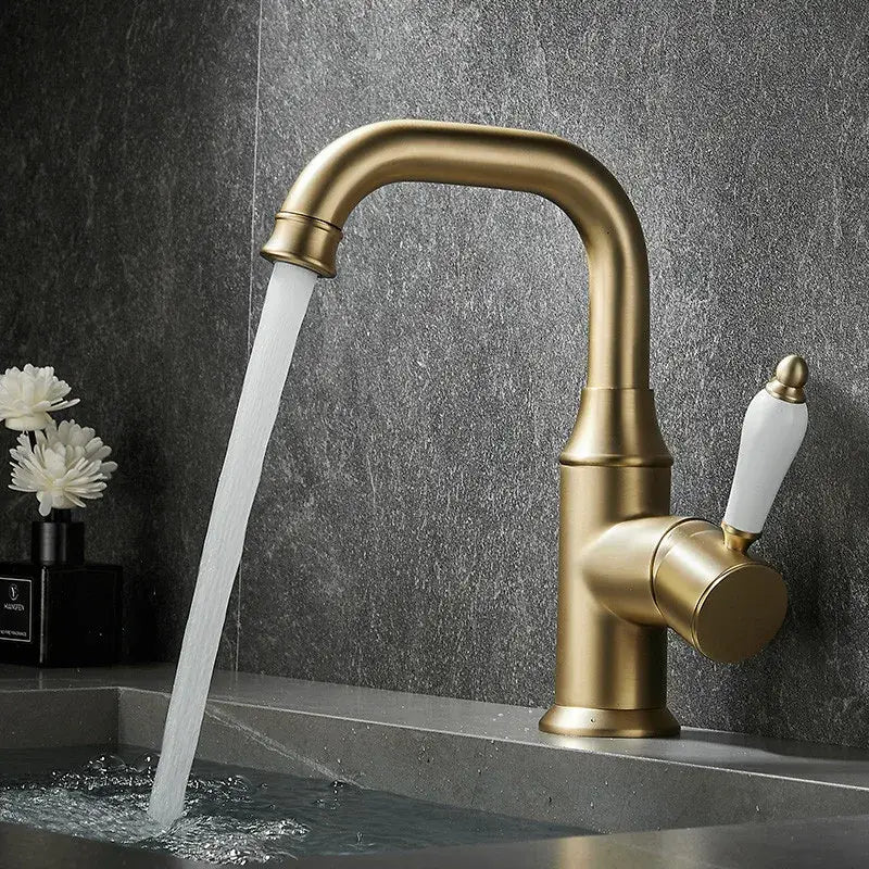 Modern brushed gold basin faucet with a curved spout and white ceramic handle by decorbites brushed gold