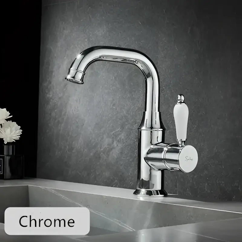 Modern brushed gold basin faucet with chrome finish, sleek curved spout, and white ceramic handle by decorbites