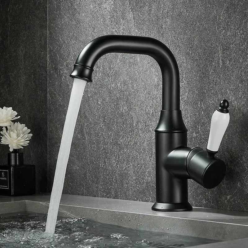 Black matte basin faucet with white ceramic handle and curved spout flowing water for decorbites brushed gold bathroom sink