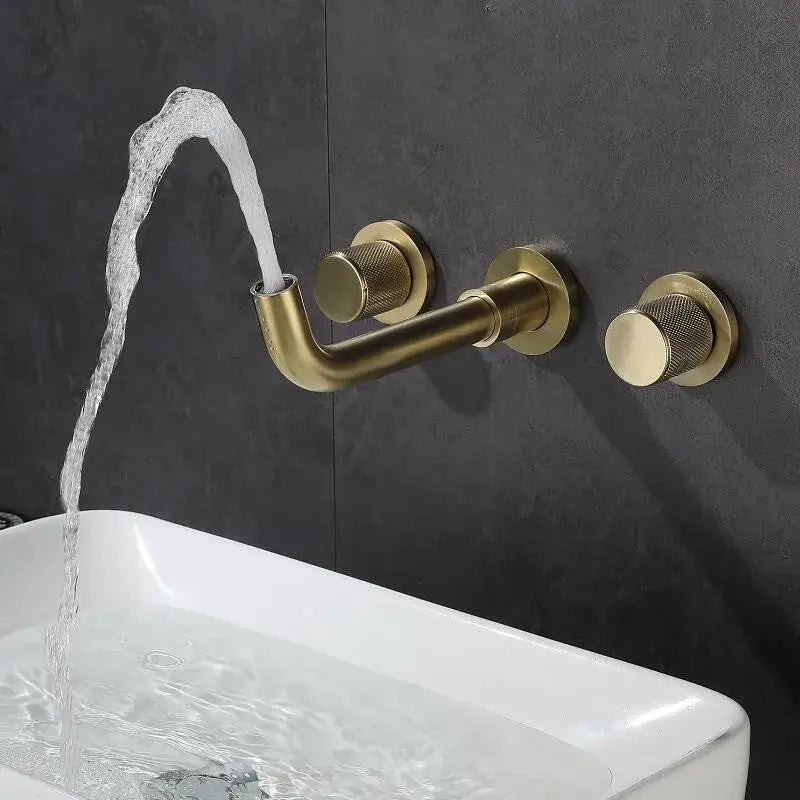 Brass-finished brushed gold basin faucet with textured knobs and curved spout flowing water into white sink decorbites brushed gold