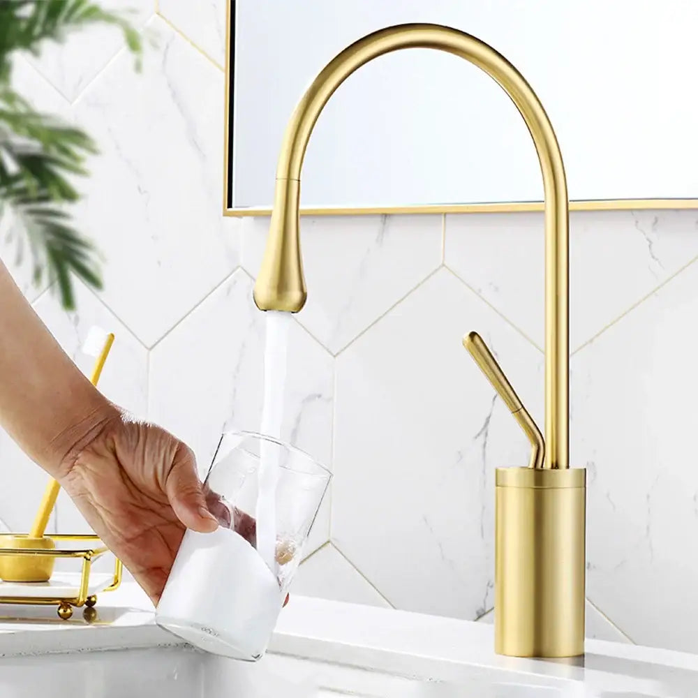 Modern brushed gold basin faucet with a sleek curved spout and cylindrical base for kitchen sink use