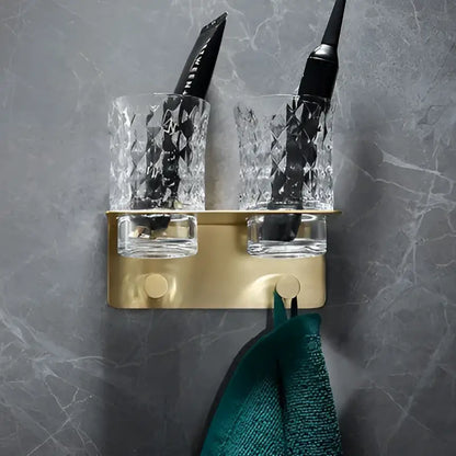 Modern brushed gold brass bath hardware set featuring a wall-mounted toothbrush holder with faceted crystal cups holding black toothbrushes