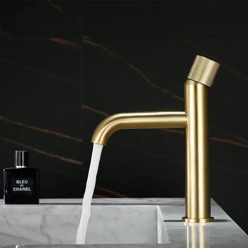 Modern brushed gold single handle basin faucet with textured knurled handle and sleek cylindrical spout for bathroom use