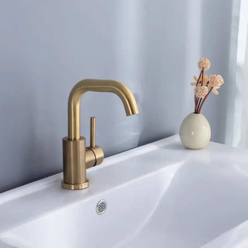 Modern brushed gold basin faucet with a single handle, brass finish, sleek curved spout, and cylindrical base for bathroom use